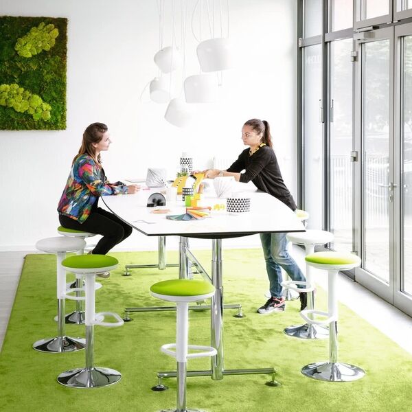 Besprechungstisch mit Hockern auf grünem Teppich im Büro